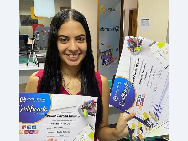 Aluna sorrindo enquanto apresenta seus certificados.
