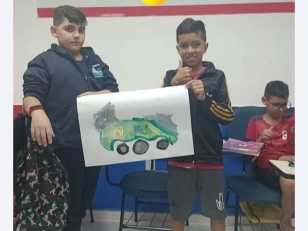 Alunos em sala de aula mostrando um desenho de um carro.