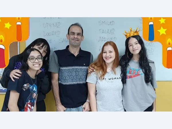 Professor e alunas reunidos em um momento de comemoração.
